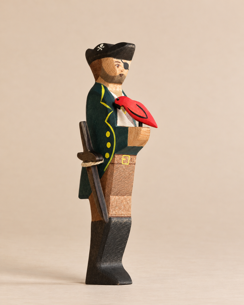 Handmade Holzwald Pirate and Parrot figure wearing an eyepatch and long coat, with a sword at his hip and a small red parrot perched on his hand as part of a collection of handmade toys.
