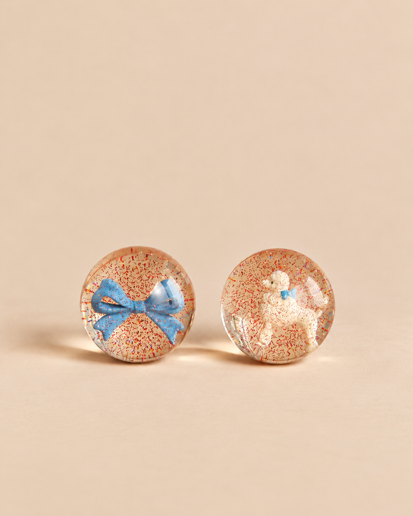 Konges Sloejd Glitter Bouncing Ball Set - Poodle & Bow featuring two clear bouncing balls filled with red glitter, one containing a blue bow and the other a white poodle figurine.