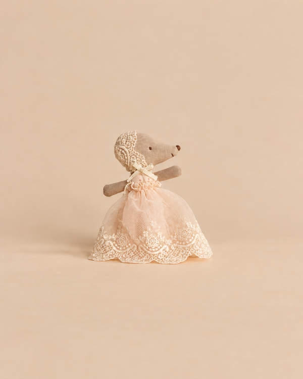 A Maileg Baby Mouse in Gown - Powder, a small cotton stuffed toy baby mouse wearing a matching bonnet and a lacy, pale pink gown.