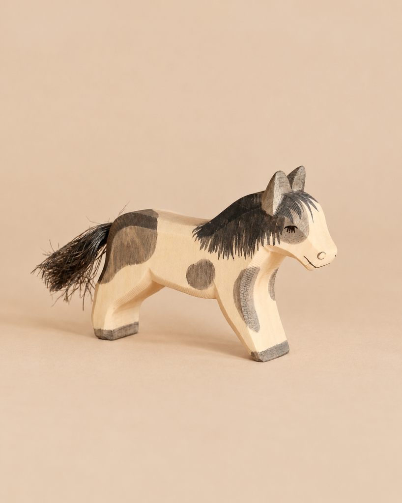 Ostheimer Pony - Running, a hand-carved wooden toy with painted grey patches and a dark brush-style tail, perfect for imaginative play.