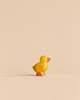 Handmade Holzwald Duckling, a small, sustainable wooden figurine with a yellow body and orange feet and beak.