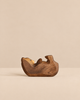 A small, hand-carved wooden Handmade Holzwald Bear Cub - Lying resting on its back, perfect for imaginative play.