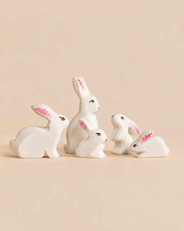 A Bumbu Handmade Wooden White Bunny Rabbit Family Set of five small, hand-painted wooden rabbits in varying sizes, each an eco-friendly toy in white with pink-lined ears.
