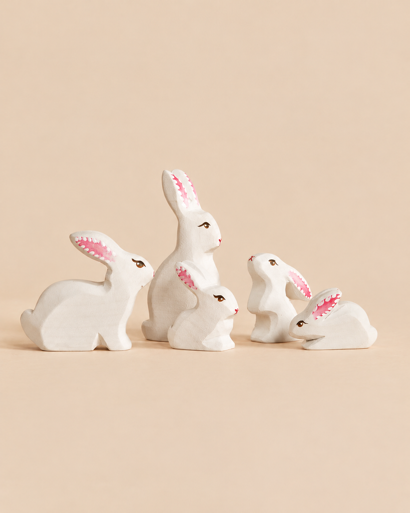 A Bumbu Handmade Wooden White Bunny Rabbit Family Set of five small, hand-painted wooden rabbits in varying sizes, each an eco-friendly toy in white with pink-lined ears.