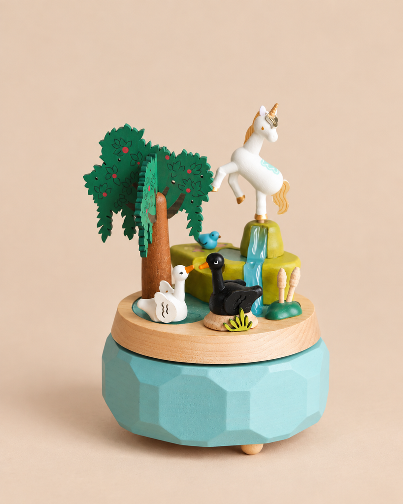 Unicorn Music Box featuring a white unicorn atop a waterfall, with a tree, a blue bird, and two swans on a pond.