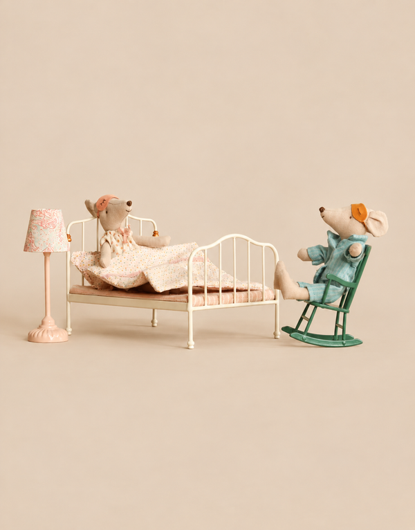 Maileg Bedroom Set with Mum & Dad featuring two mice in pajamas; one sits in a vintage bed wearing an eye mask, while the other sits in a small green rocking chair with an eye mask pushed up, beside a miniature lamp.
