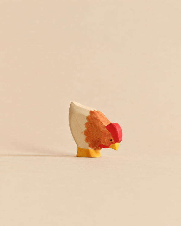 A small Handmade Holzwald Hen wooden figurine with painted red and orange plumage.