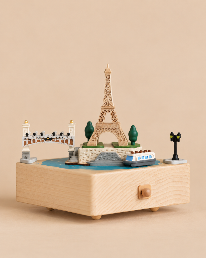A Paris Music Box featuring a miniature Eiffel Tower, a bridge, a boat, and a lamp post on its top surface.