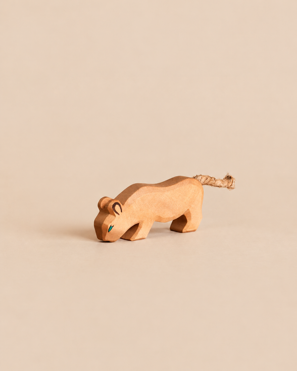 An Ostheimer Lion handcrafted wooden toy in a crouching position with a rope tail, designed for imaginative play.