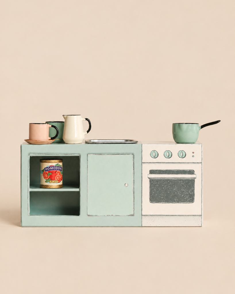 A Maileg Kitchen Counter, Mouse Size, featuring a stove, sink, and open shelving holding a toy can of tomatoes, mugs, and a saucepan.