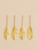 Four gold-colored brass Ferm Living Oak Leaf Ornaments - Set of 4 - Brass, each shaped like an oak leaf and hanging from a thin chain.