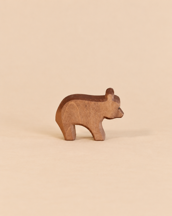 A handcrafted wooden Ostheimer Small Bear - Running figurine in a standing position, perfect for imaginative play.