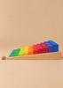 Grimm’s Stepped Counting Blocks - Large, a set of rainbow-colored wooden blocks in ascending heights arranged on a slanted tray, with a small snail shell resting on the surface nearby.