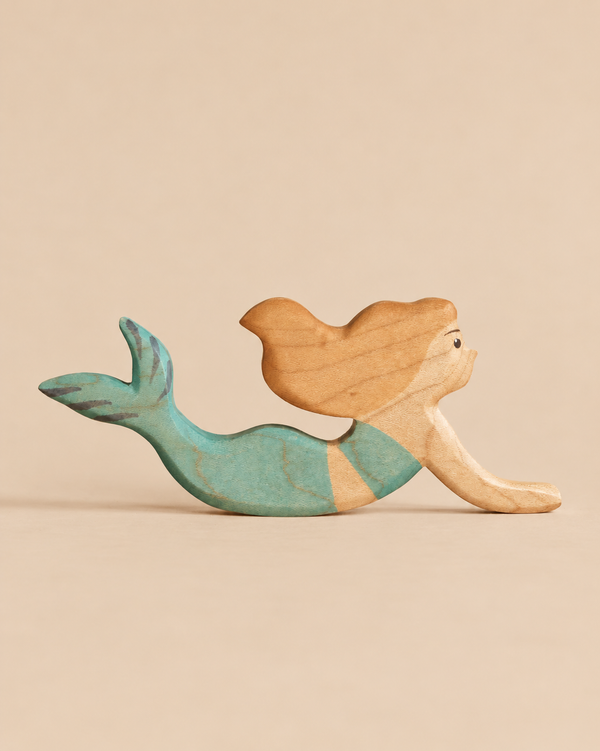 A Handmade Holzwald Mermaid wooden toy with a natural wood-toned top and a teal-colored tail.