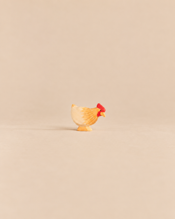 Ostheimer Hen Standing - Ochre, a handcrafted wooden hen figurine with yellow and ochre plumage and a red comb.