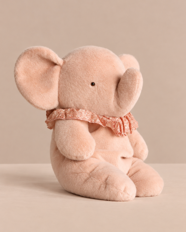 A soft pink Maileg Elephant Plush, Big - Powder sitting upright, wearing a ruffled lace collar as a charming stuffed animal.