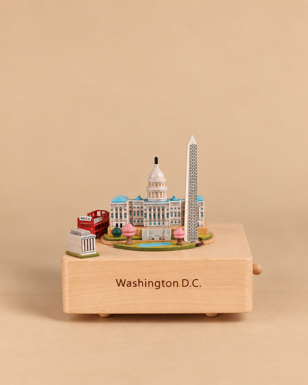 A Washington D.C. Wooden Music Box featuring miniature models of the Capitol building, Washington Monument, and a red double-decker bus, with “Washington D.C.” engraved on the front.