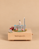 A Washington D.C. Wooden Music Box featuring miniature models of the Capitol building, Washington Monument, and a red double-decker bus, with “Washington D.C.” engraved on the front.
