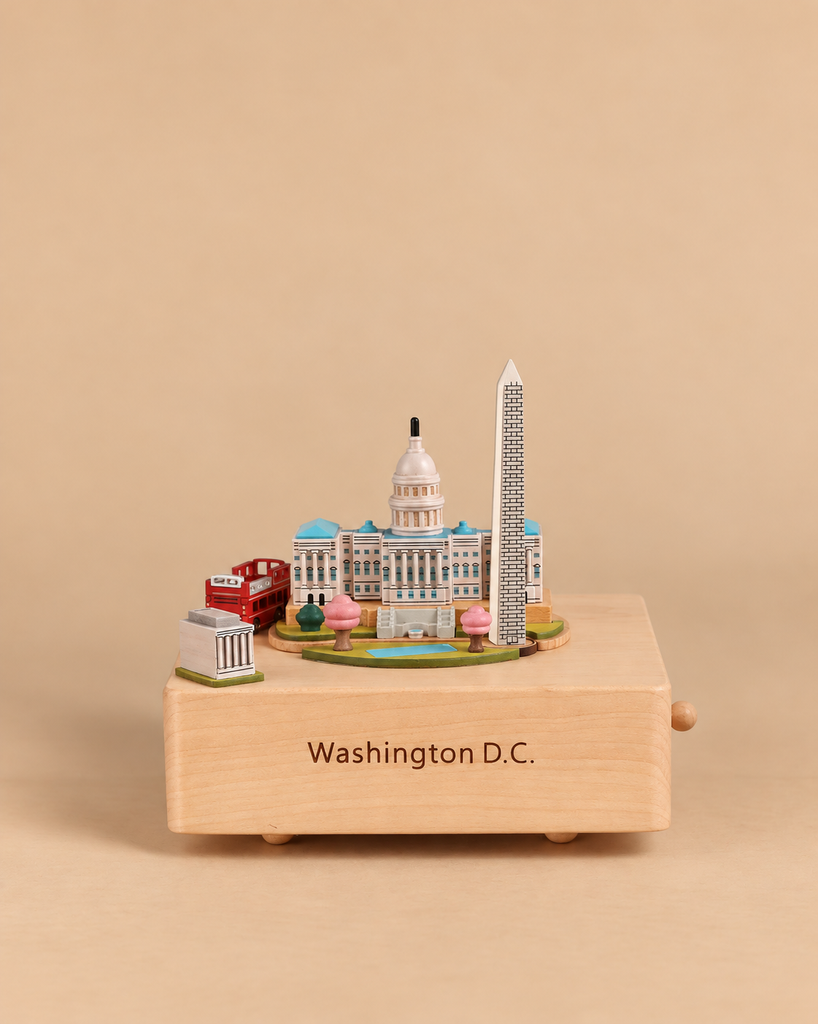 A Washington D.C. Wooden Music Box featuring miniature models of the Capitol building, Washington Monument, and a red double-decker bus, with “Washington D.C.” engraved on the front.
