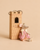 A Maileg Queen Mouse, Mum wearing a crown and a pink patterned dress sits in a castle hall in front of a cardboard tower that reads, “Let the Story Begin.”