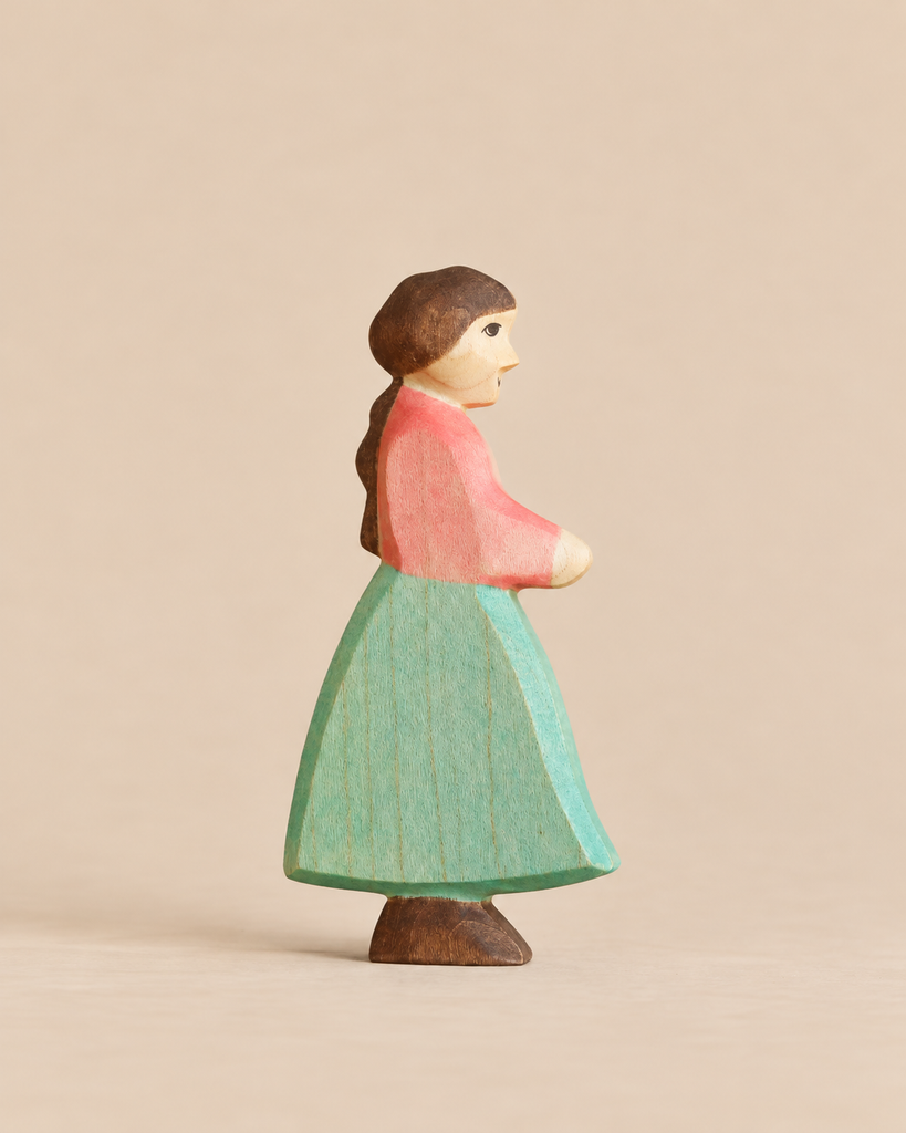 Handmade Holzwald Goose Girl figurine, hand-carved from wood as a girl in a pink top and green skirt for imaginative play.