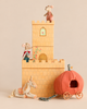 Two Big Sister Mouse plush toys in royal attire from the Maileg Fairytale Set stand on a castle, with a plush unicorn and an orange pumpkin carriage on the ground.