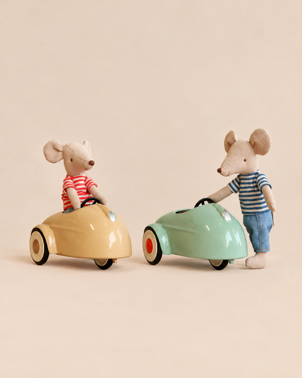 The Maileg Big Brother LouiMax and Big Sister Stella Adventure Set features two mice in striped shirts, one sitting in a yellow toy car and one standing next to a green toy car.