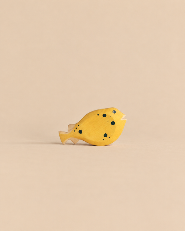 Handmade Holzwald Pufferfish, a yellow wooden toy with black spots designed as a sustainable product.