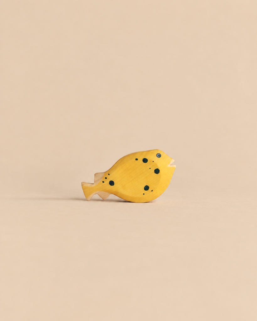 Handmade Holzwald Pufferfish, a yellow wooden toy with black spots designed as a sustainable product.