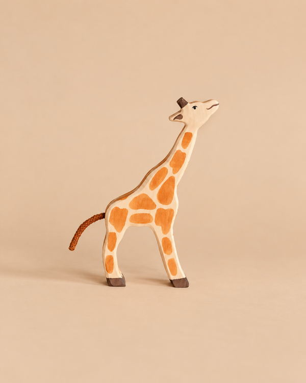 Holztiger Small Feeding Giraffe: a handcrafted wood toy with orange spots, a braided tail, and its neck extended upward.