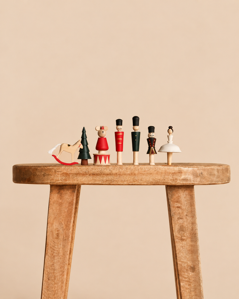 A row of six Sabo Concept Wooden Nutcracker Figurines, including a rocking horse, a tree, and several characters, standing on a wooden stool.