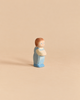 A small handcrafted Ostheimer Toddler wooden figurine of a toddler wearing a blue outfit.