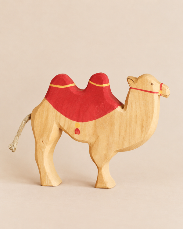 Hand-carved Ostheimer Camel With Saddle featuring a red saddle and a rope tail, perfect for imaginative play.