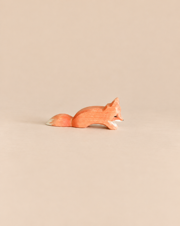 An Ostheimer Small Fox - Creeping, a small, handcrafted wooden fox figurine in a crouching position, perfect for imaginative play.