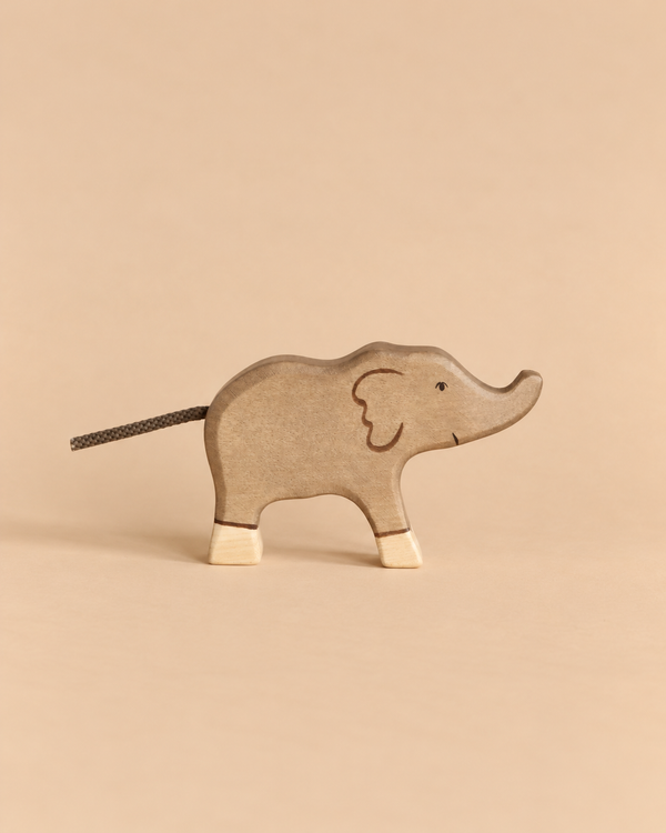 A Holztiger Elephant, Small, handcrafted from wood with a cord tail and light-colored feet.