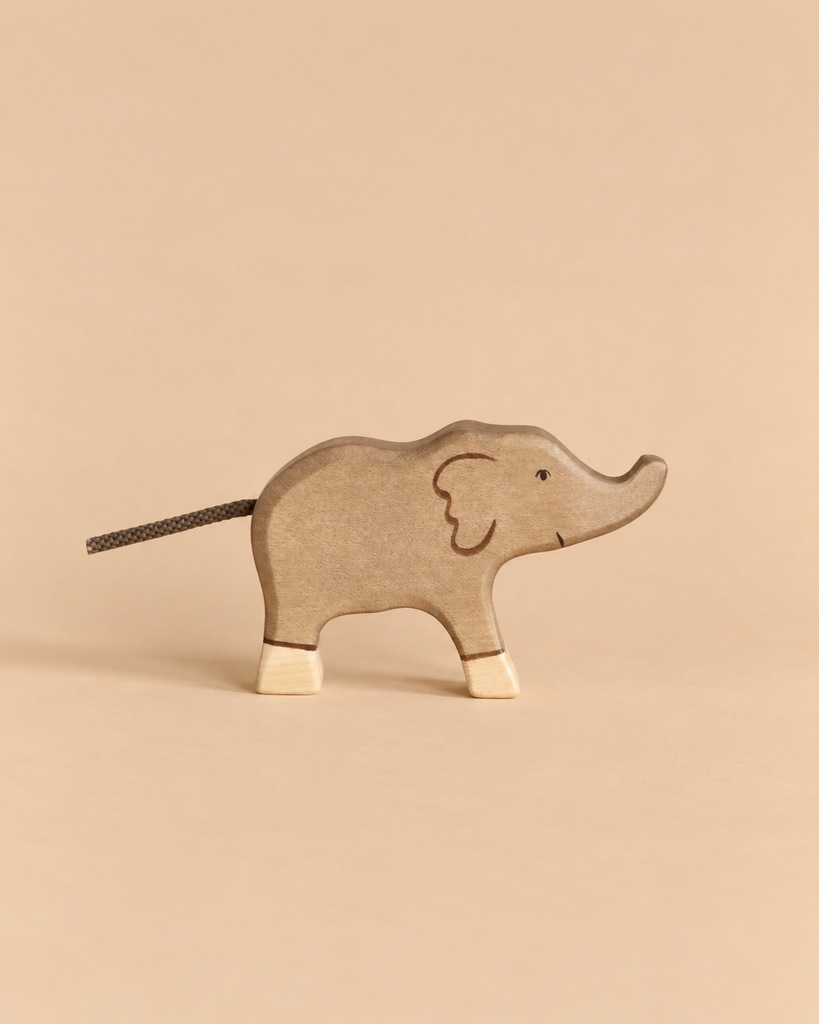 A Holztiger Elephant, Small, handcrafted from wood with a cord tail and light-colored feet.