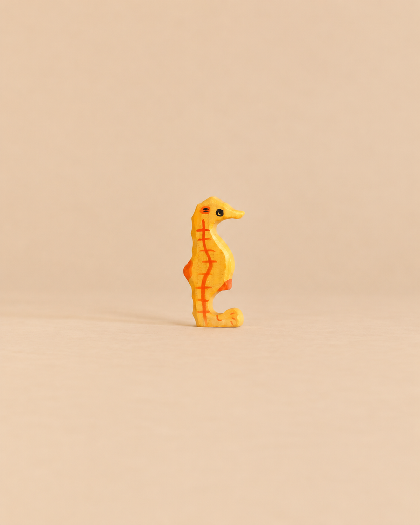 Holztiger Seahorse, a handcrafted wooden toy in yellow with orange stripes.