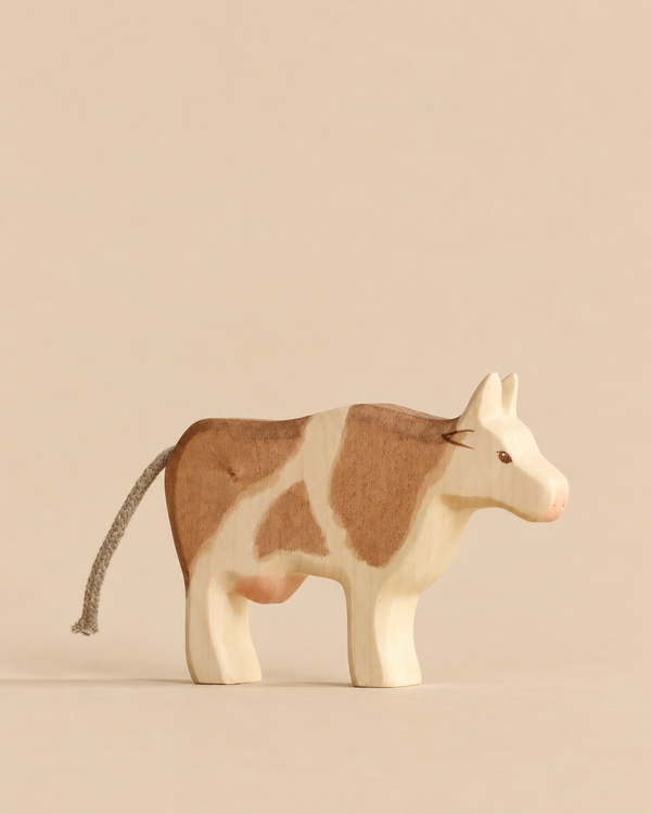 Handmade Holzwald Cow wooden toy with brown patches and a rope tail.