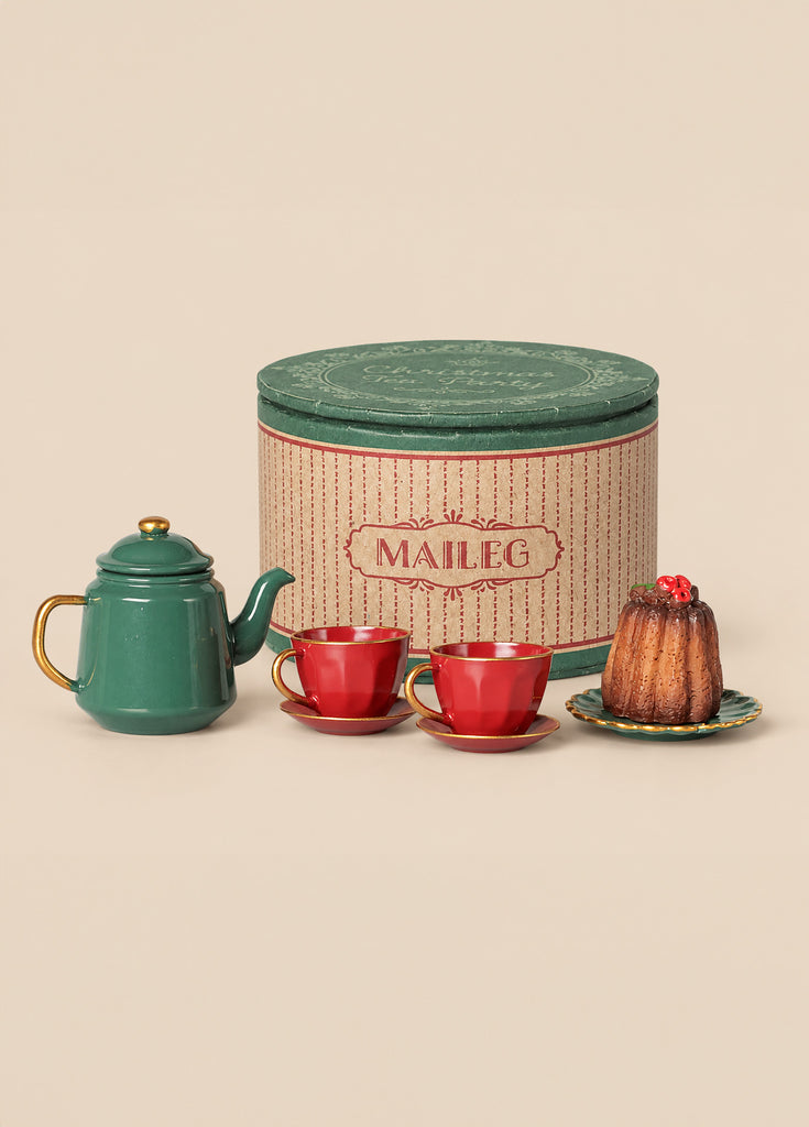A Maileg Christmas Tea Party, Mouse - Red/Green featuring a green teapot, two red teacups on saucers, and a small dessert on a plate, all set in front of a round, decorative storage tin.