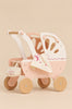 A pink and cream Retro Wooden Doll Stroller with four wheels, a matching bag, and a patterned fabric blanket draped over the hood.