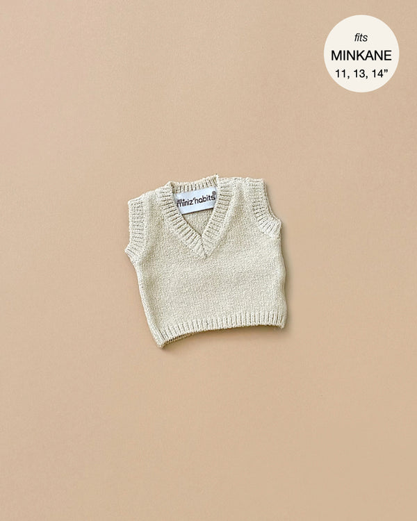 The Minikane Doll Clothing features a cream knit Leonardo tank top suitable for dolls, displayed against a light brown backdrop. It is designed to fit Minikane Babies sized 11, 13, and 14 inches.