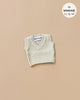 The Minikane Doll Clothing features a cream knit Leonardo tank top suitable for dolls, displayed against a light brown backdrop. It is designed to fit Minikane Babies sized 11, 13, and 14 inches.