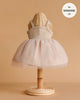 The Minikane Doll Clothing | Rosella Tutu - Pink is a sleeveless dress with a tulle skirt, shown on a wicker mannequin against a beige background. Designed in classic French style, it fits 13-inch Minikane dolls.