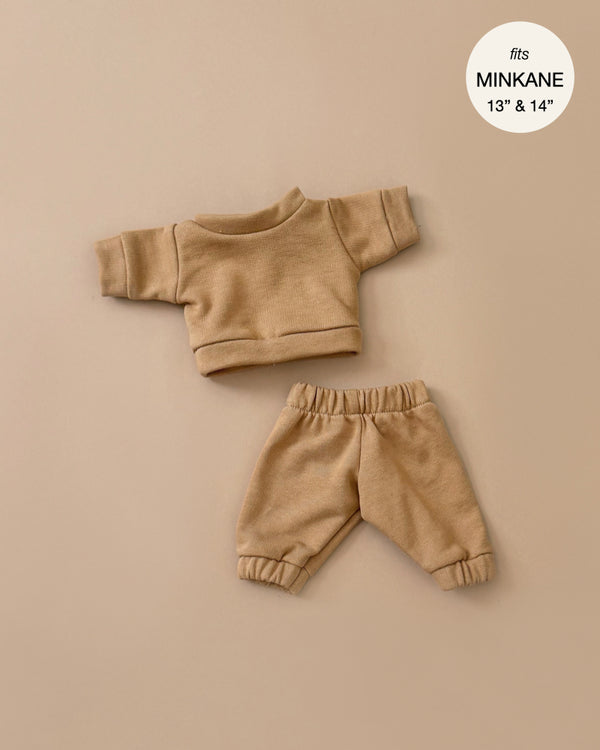 The Liam Havana Fleece Set is a two-piece tan outfit with a long-sleeved top and elastic-waist pants for 13" and 14" Minikane dolls. Made in France, it features "fits MINKANE" on the beige background label and is hand washable.