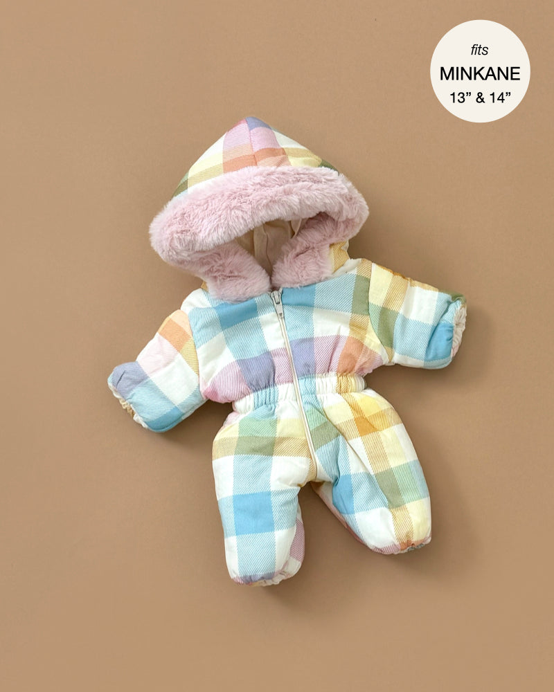 The Minikane Doll Clothing | Pastel Plaid Ski Suit, designed for 13" and 14" Minikane dolls, features a fluffy pink faux fur trim hood. Displayed on a beige background, the suit includes a plaid pastel color scheme with a front zipper and elastic cuffs.