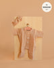 The Minikane 11" Doll Clothing | Lili Jumpsuit & Headband in Cotton Gauze - Latte features a peach-toned textured jumpsuit with three white buttons and a matching headband, displayed on a wooden board—perfect for stylish doll lovers.