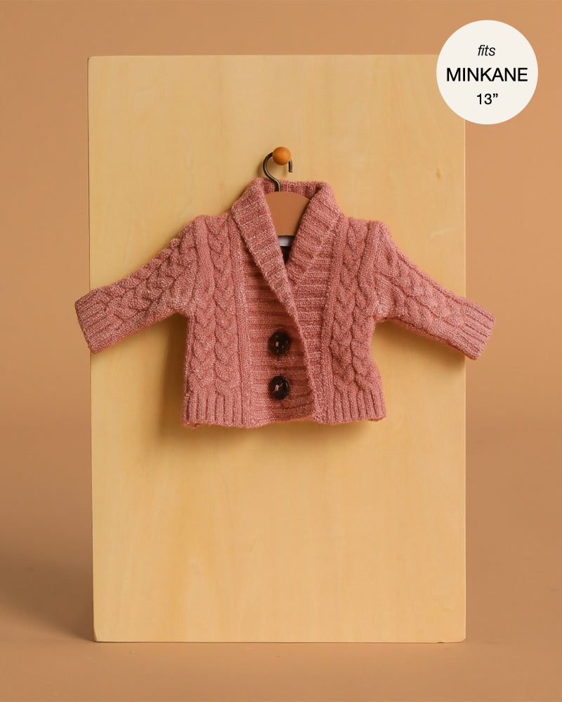 The Gil Knitted Vest in Tea Pink wool for Minikane 13" dolls is shown on a wooden board with a hanger. A round label at the top right states: "fits Minikane 13 inch doll clothes.