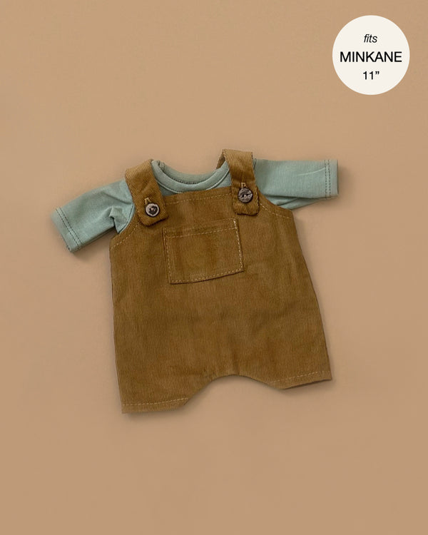 A khaki overall set matched with a green jersey t-shirt, designed for an 11" baby doll, displayed on a beige background, embodies a hint of France's enchanting style.