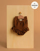 The Maïa Ruffled Leotard in Soft Lycra – Chocolate Brown hangs on a wooden hanger against a beige background, designed to perfectly fit Minikane 13" dolls. "Fits MINIKANE 13''" label shown in the corner.