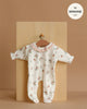 The Minikane 11" Doll Clothing | Camille Onesie in Ribbed Cotton - Pink Flowers features a white ribbed romper with pink ruffle collar and floral print, plus a matching collar and headband. Shown on a wooden hanger, fits MINKANE 11".